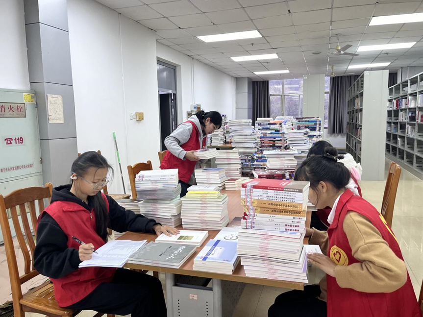 志愿者们在学校图书馆为新书编码、登记入库
